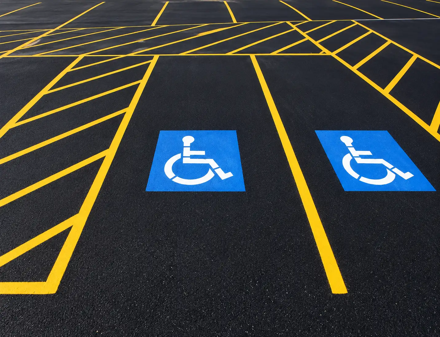 Yellow parking lines and blue accessible-space markings on dark asphalt