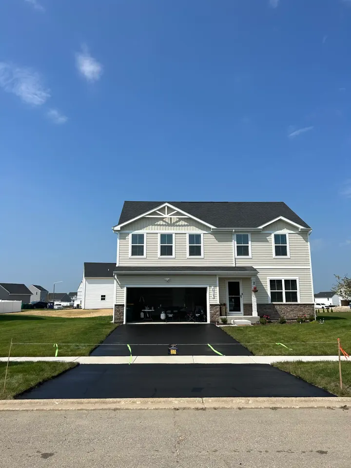 Driveway outside a large light-colored house with an open garage