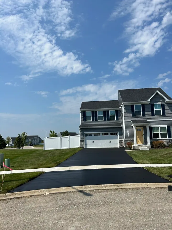 Wide view of a driveway beside neighboring homes and concrete sidewalk