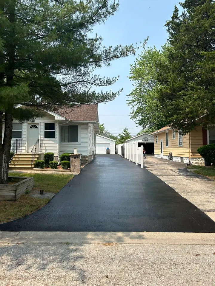 Long coated driveway running between a house and a neighboring fence