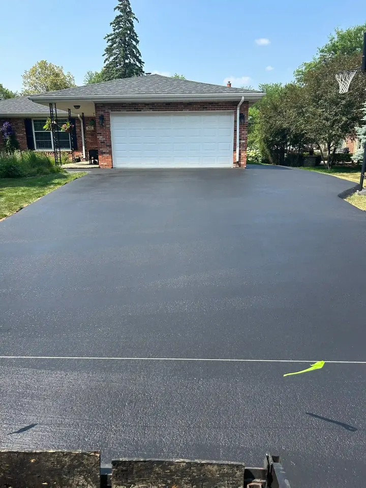 Wide dark driveway in front of a white two-car garage