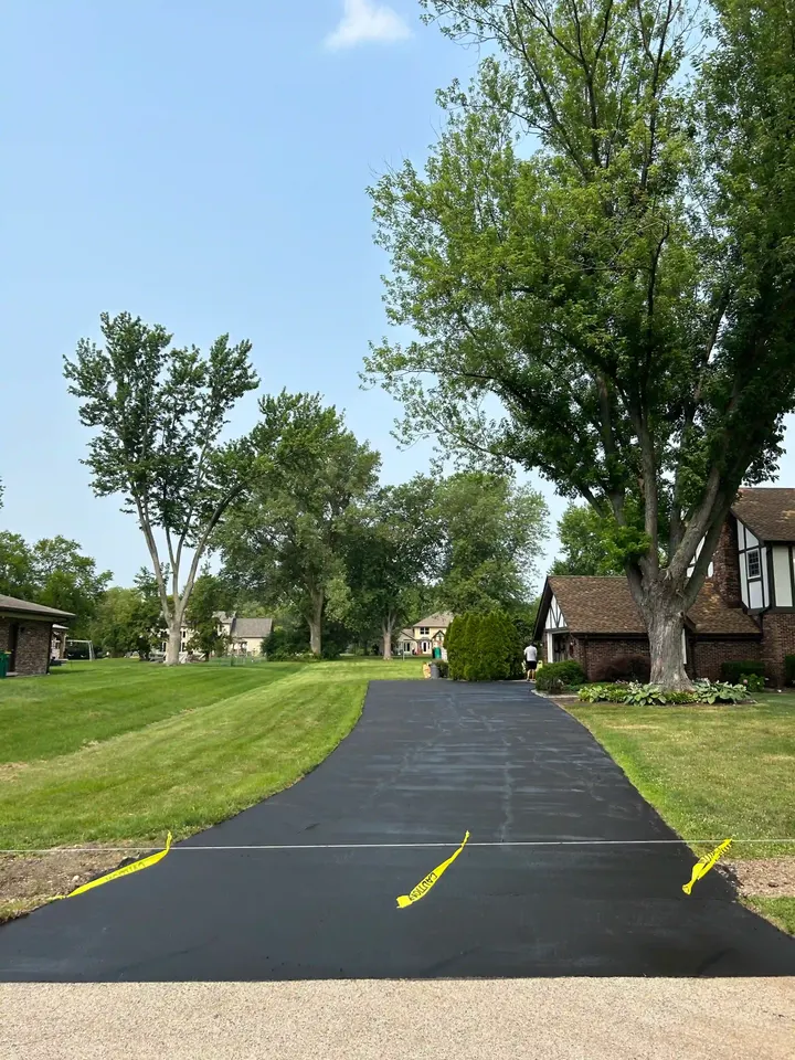 Long narrow driveway beside a lawn with yellow safety tape at the entrance