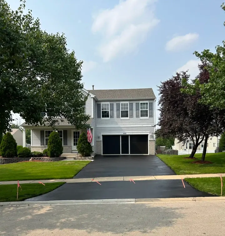 Driveway outside a white two-story house with a dark garage opening