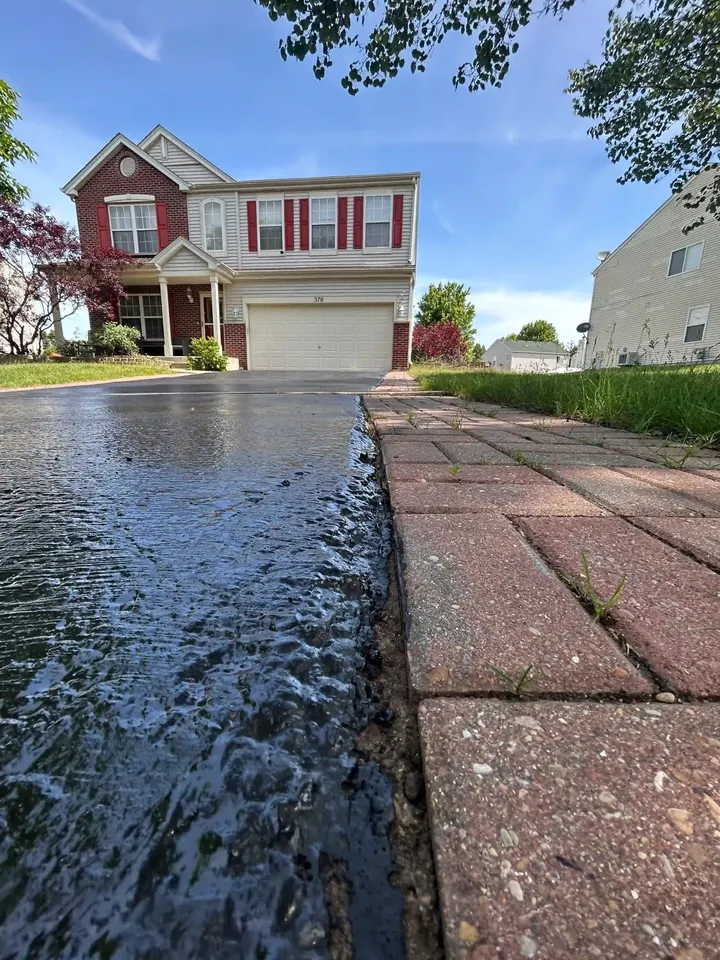 Close view of dark driveway asphalt alongside a brick border