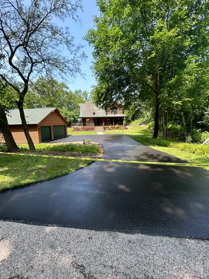 Sealcoated driveway with a gravel apron and a small wooden shed nearby