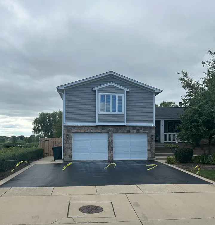 Dark driveway outside a blue two-story house