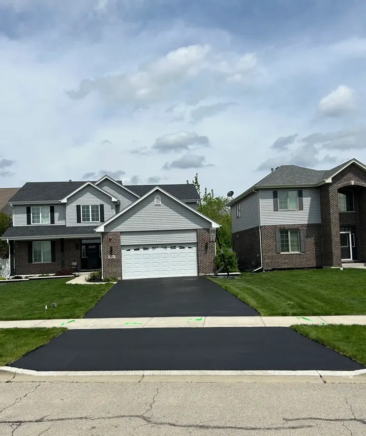 Coated driveway and apron outside a light-colored two-story home