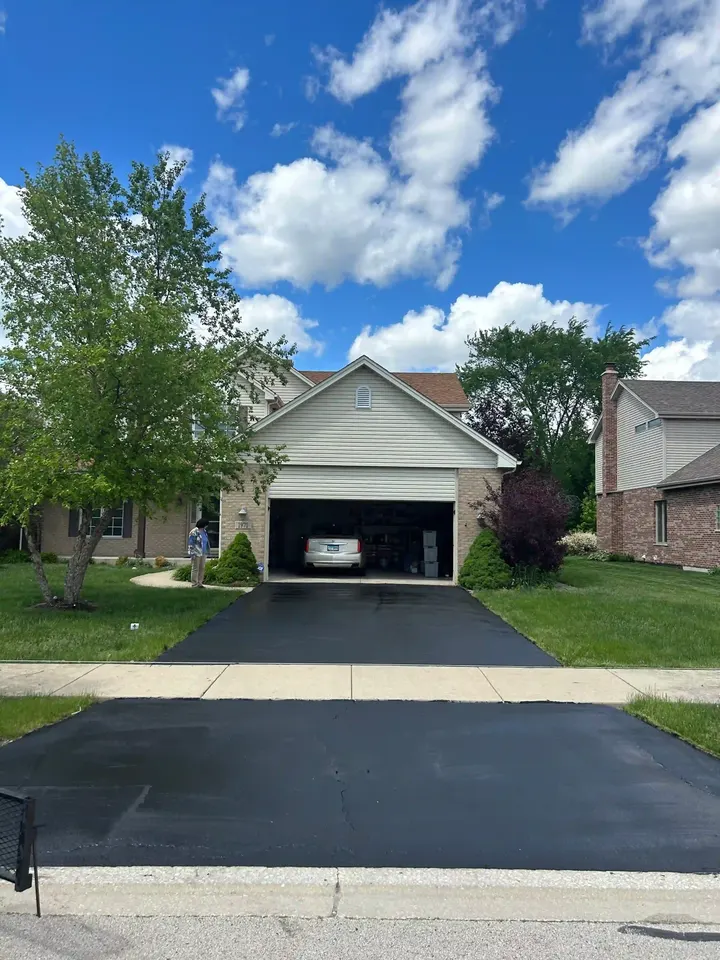 Sealcoated driveway leading toward an open detached garage