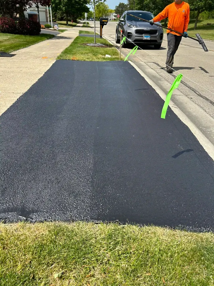 Coated driveway apron with a crew member near the sidewalk