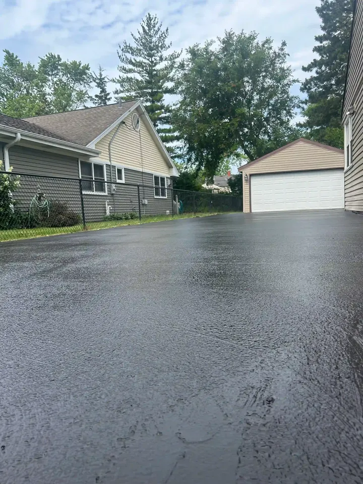Driveway surface extending toward a white garage under trees
