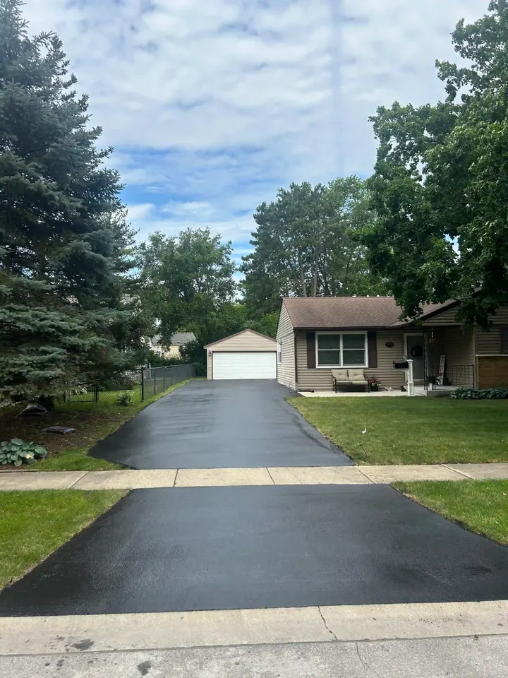 Long residential driveway and apron with trees along the lawn