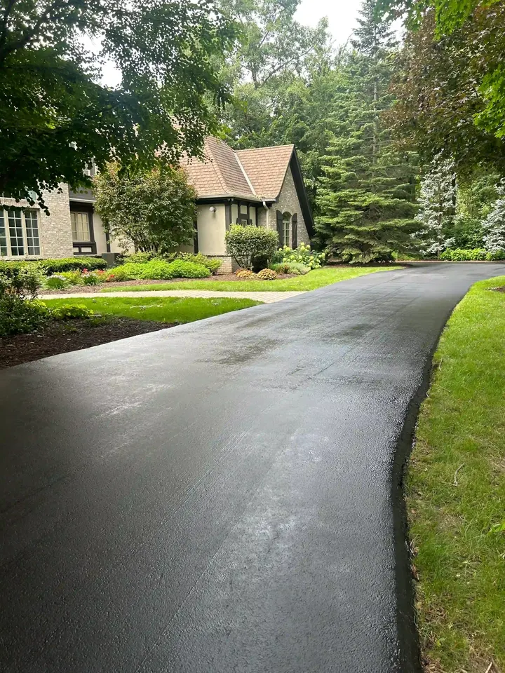 Coated curved driveway with landscaped edges outside a house